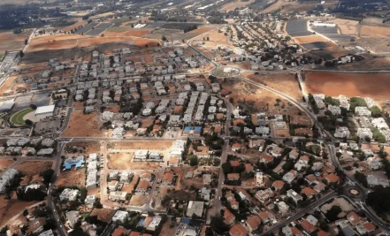 מבט מלמעלה על שכונת מגורים, כבישים ושטחים פתוחים.